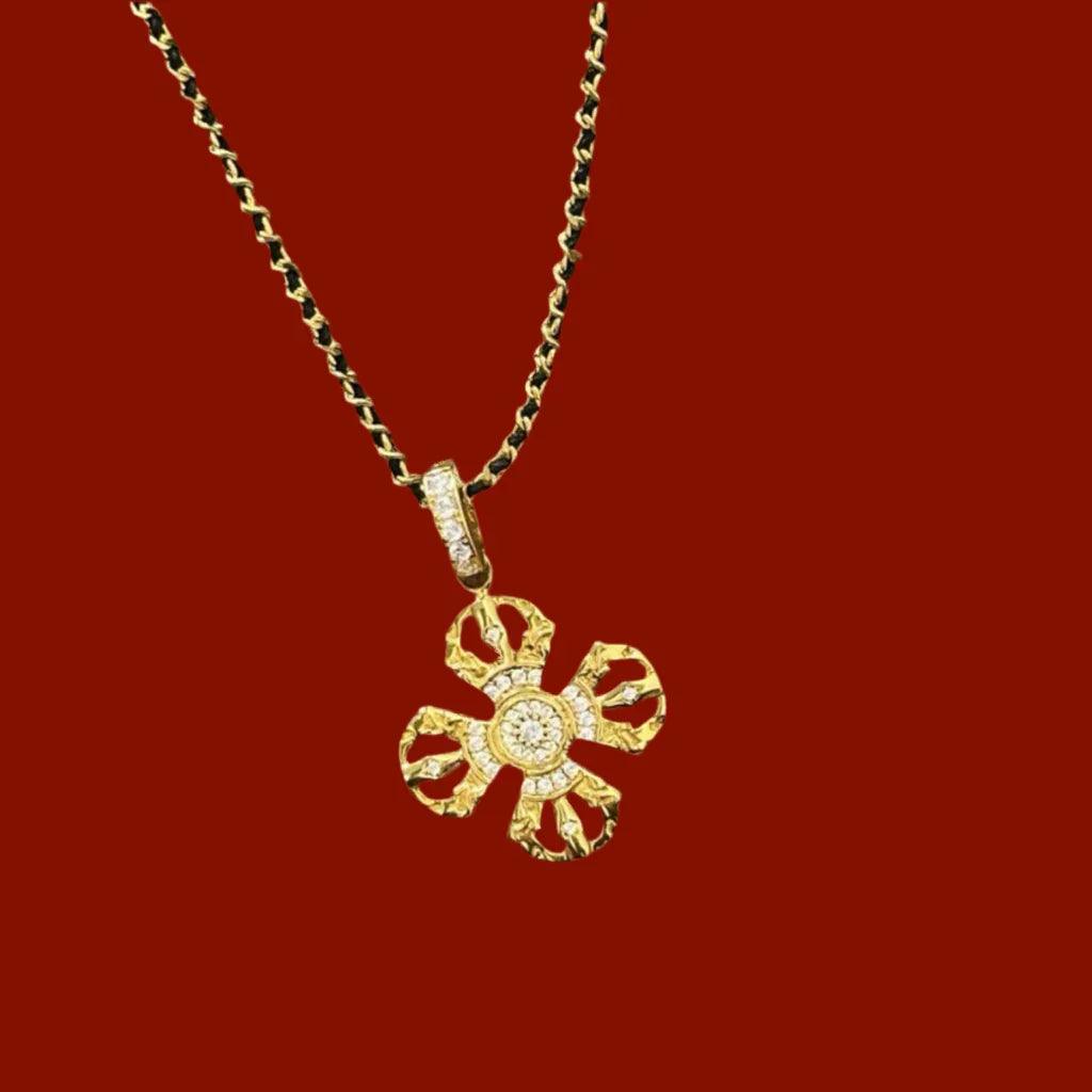Gold floral pendant necklace with intricate design and gemstone accents on dark red background