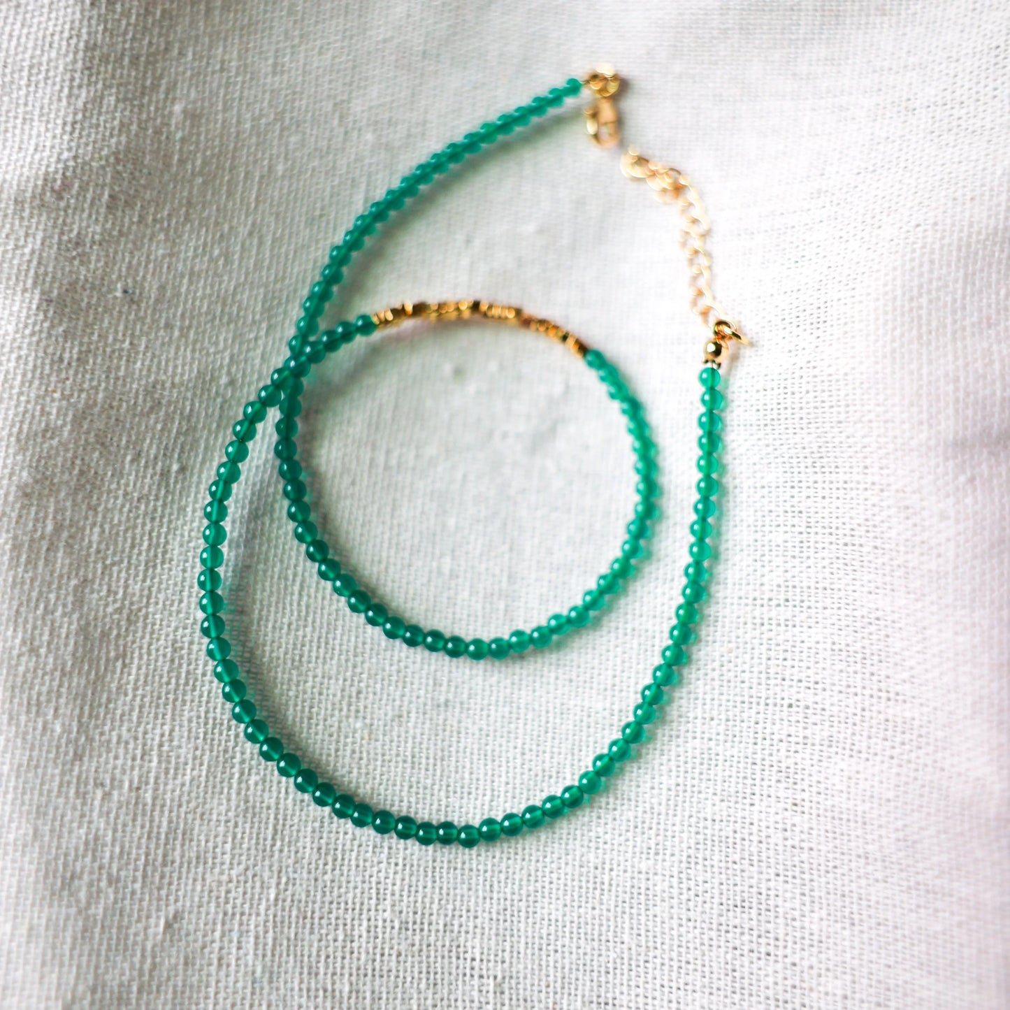 Mayan green agate and golden nugget beaded necklace on white textured fabric