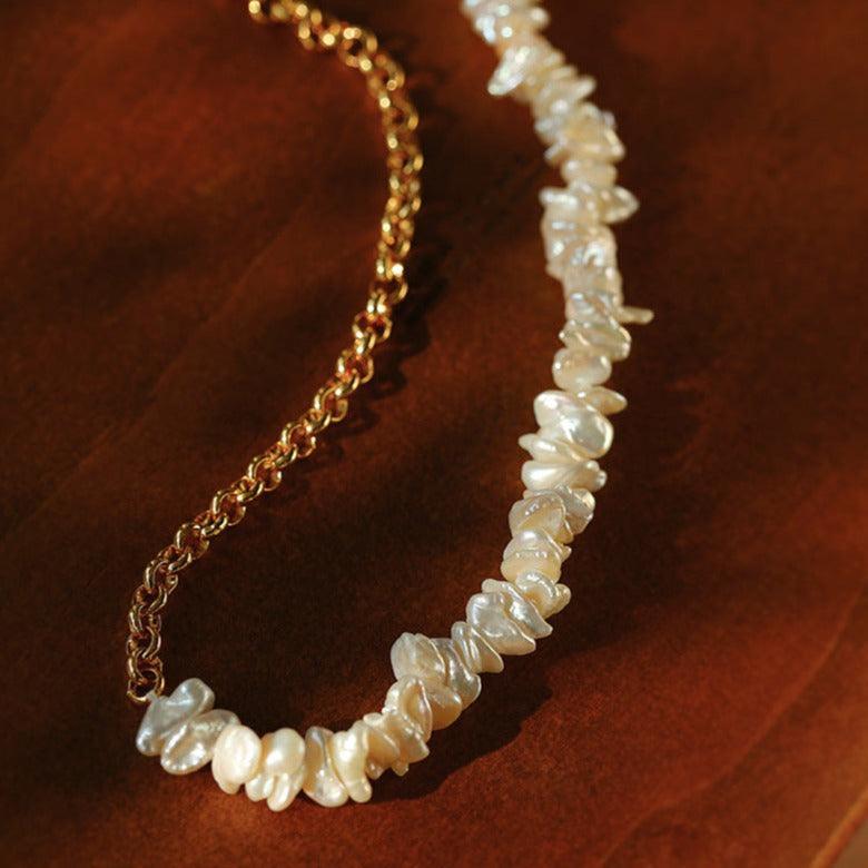 Baroque pearl necklace with gold chain on a brown textured surface