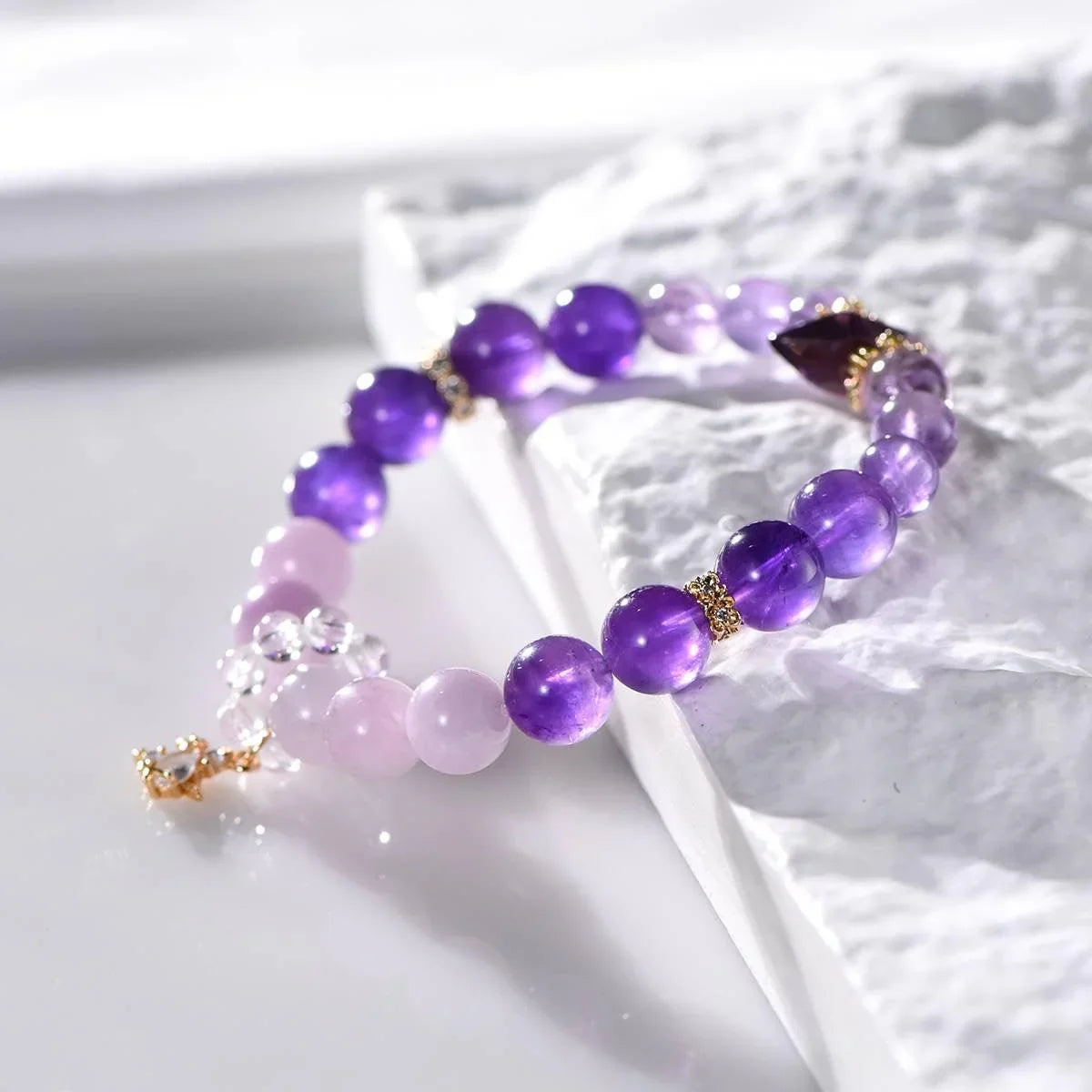 Violet flame bracelet with amethyst, lepidolite, herkimer diamond beads on white textured surface