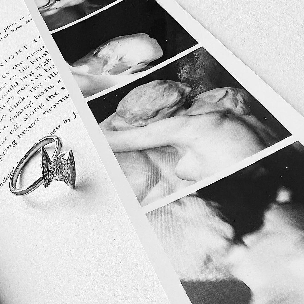 Silver lightning bolt ring with round diamond on black and white art book page