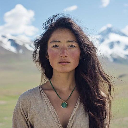Portrait of woman with long dark hair and green pendant necklace in mountainous outdoor setting