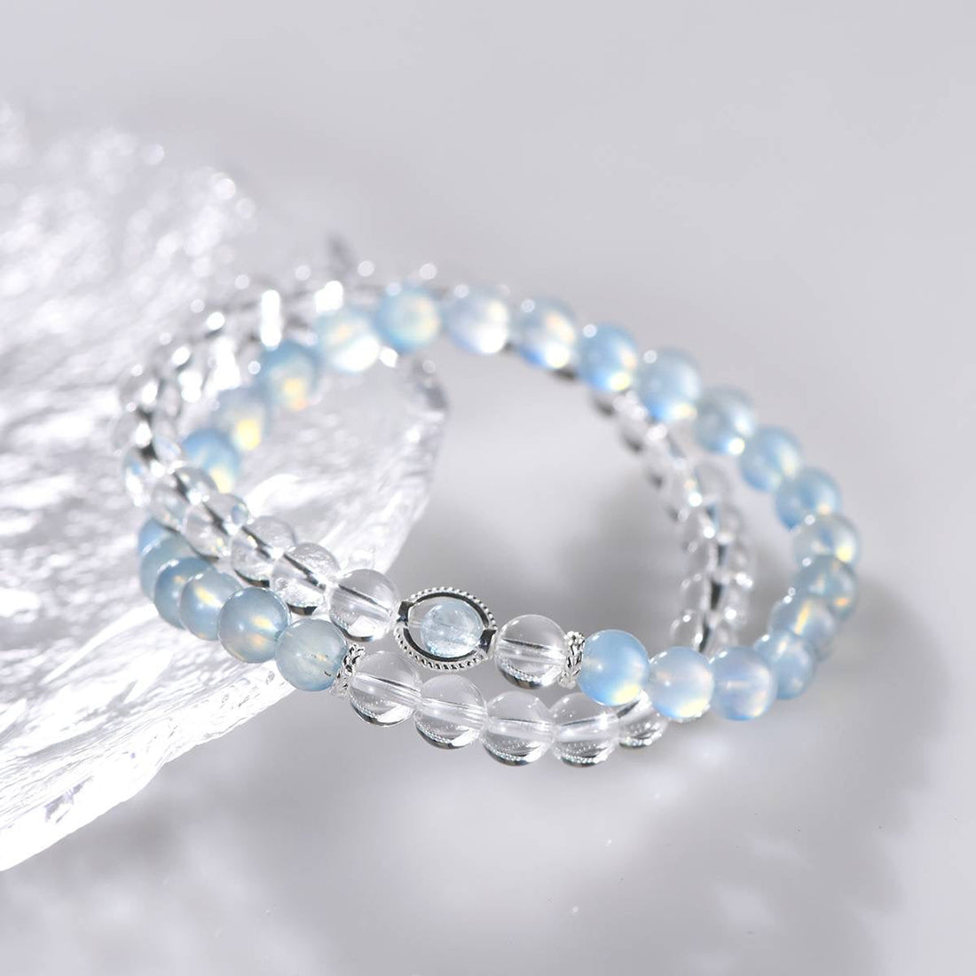 Elegant double-strand bracelet with blue opal and clear quartz beads on reflective surface
