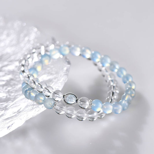 Elegant double-strand bracelet with blue opal and clear quartz beads on reflective surface