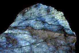 Close-up of iridescent labradorite mineral with blue and green flashes on dark background