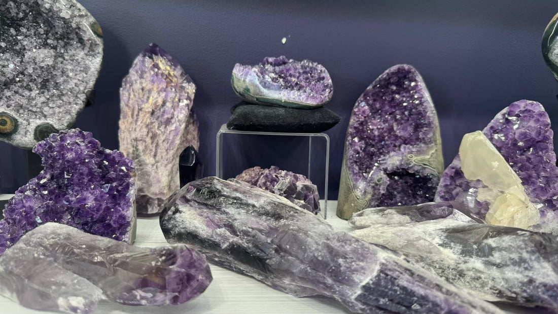 Assorted amethyst crystals and geodes in various shapes and sizes on a display with a purple background