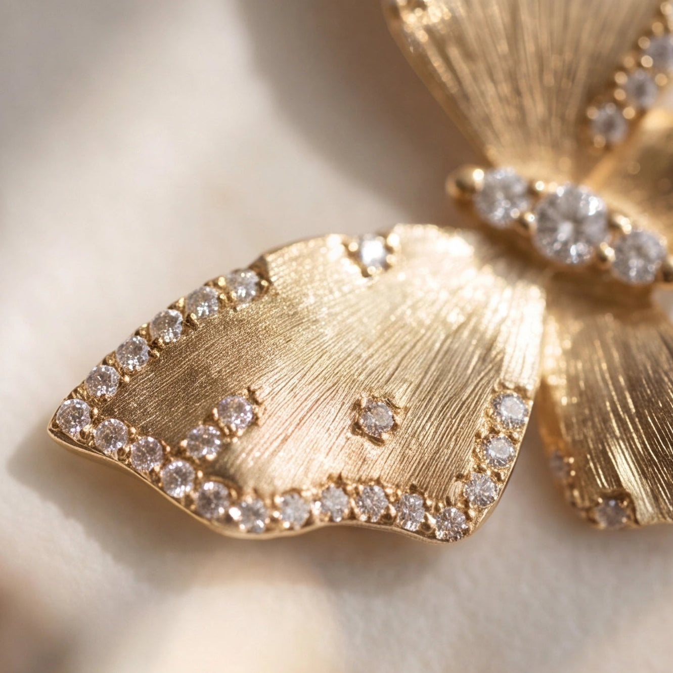 Gold butterfly earrings with diamond accents on a light background