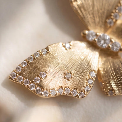 Gold butterfly earrings with diamond accents on a light background