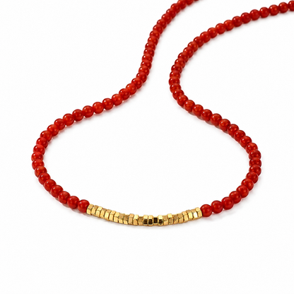 Necklace with red beads and a gold clasp on a white background