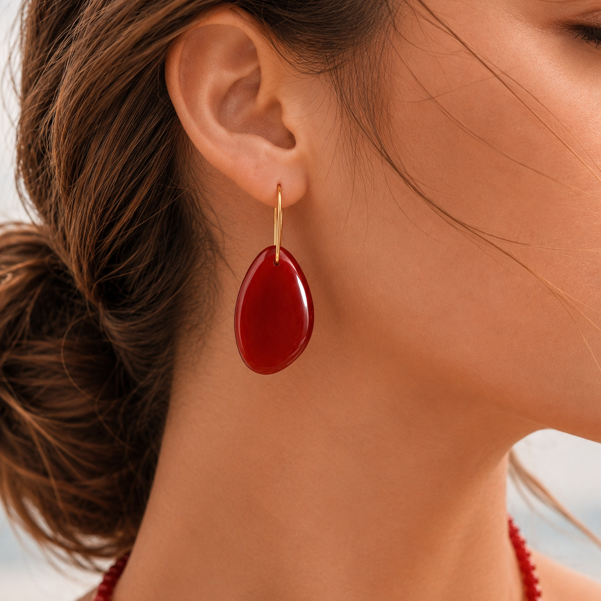 Close-up of a woman wearing a red teardrop earring with a blurred background