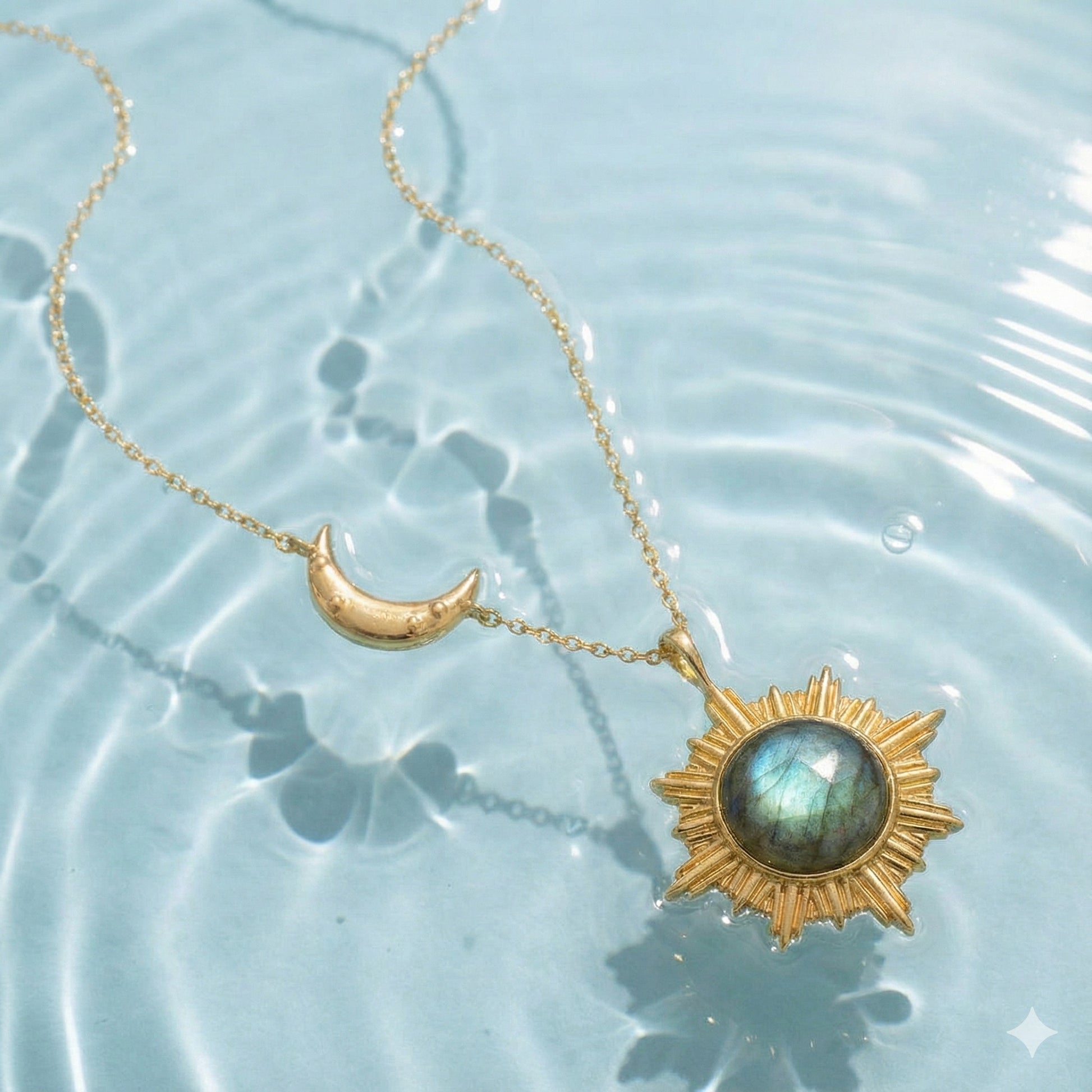 Gold sun and crescent moon necklace with blue gemstone pendant submerged in water