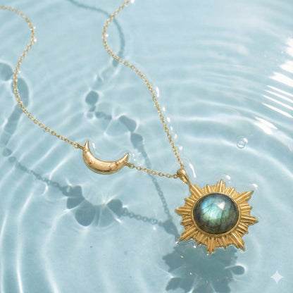 Gold sun and crescent moon necklace with blue gemstone pendant submerged in water
