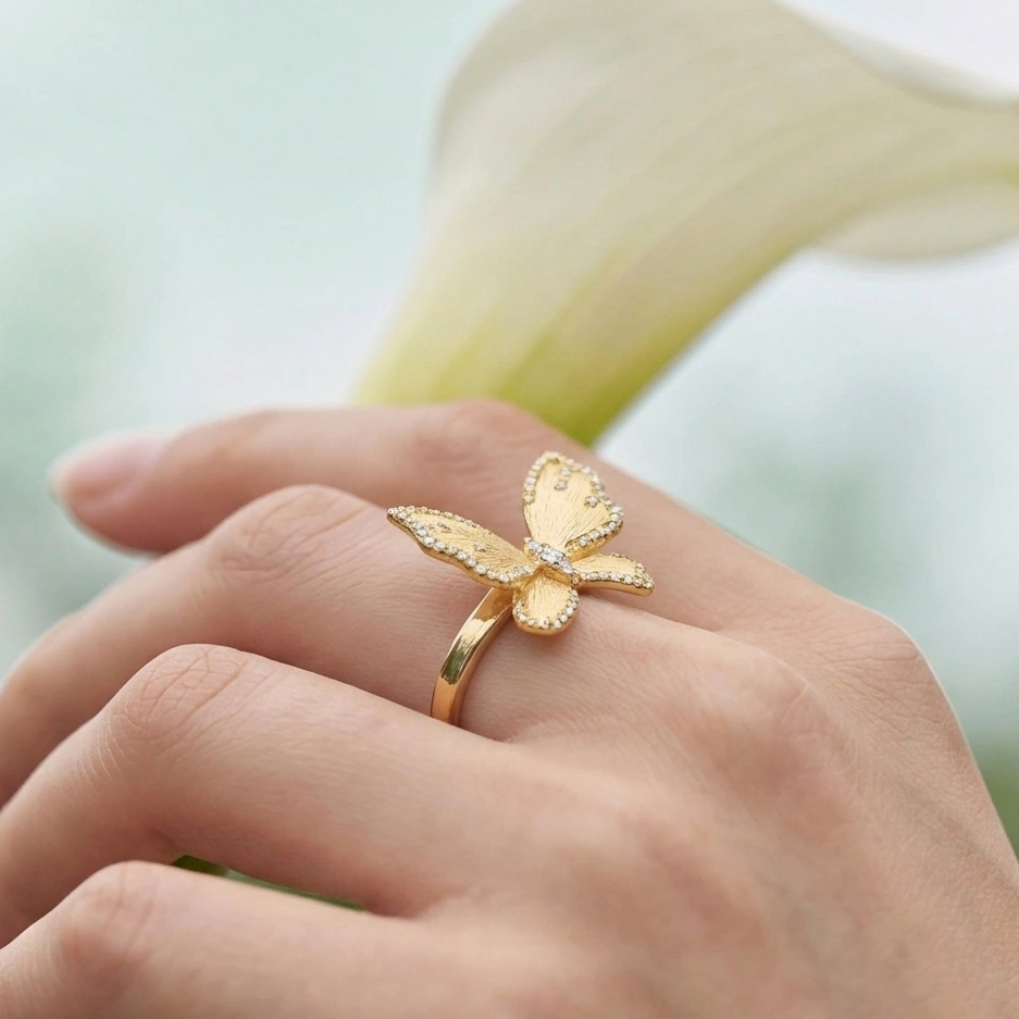 Gold butterfly ring on a person's finger with a blurred background